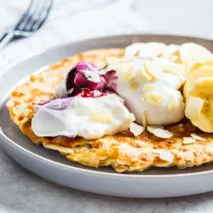 Puszysty omlet z bananem, jogurtem, musem jagodowym i płatkami migdałów. Idealne śniadanie.