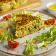 Pyszny omlet z piekarnika z warzywami, podany z sałatką i pomidorkami.