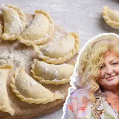 Surowe ciasto na pierogi, jak u Magdy Gessler, ułożone na desce, obok uśmiechniętej restauratorki.