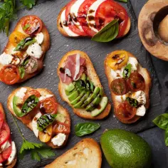 Kolorowe kanapki z pomidorami, mozzarellą, awokado i bazylią, skropione balsamicznym sosem. Idealne na letnie przyjęcie.