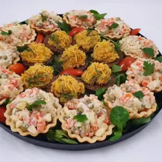 Talerz pełen pysznych przekąsek typu finger food: babeczki z sałatką jarzynową i kanapeczki z pastą.