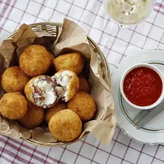 Koszyk pełen chrupiących arancini, czyli smażonych kulek ryżowych z serem i wędliną. Idealne na przekąskę!