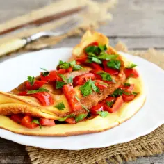 Omlet z papryką i natką pietruszki na białym talerzu.