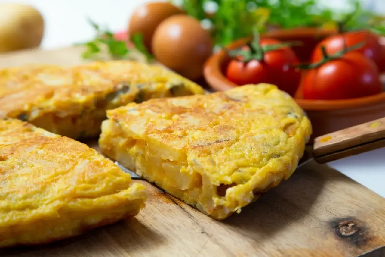 Pyszna tortilla ziemniaczana, idealna do smażenia na oliwie z oliwek. Podana z pomidorami i jajkami.