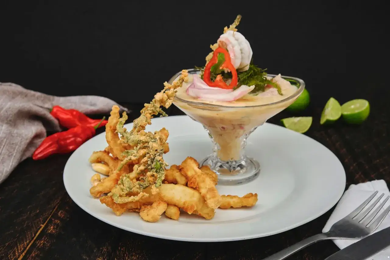 Pyszne ceviche z krewetkami i chrupiącymi kalmarami, podane z limonką i papryczkami.