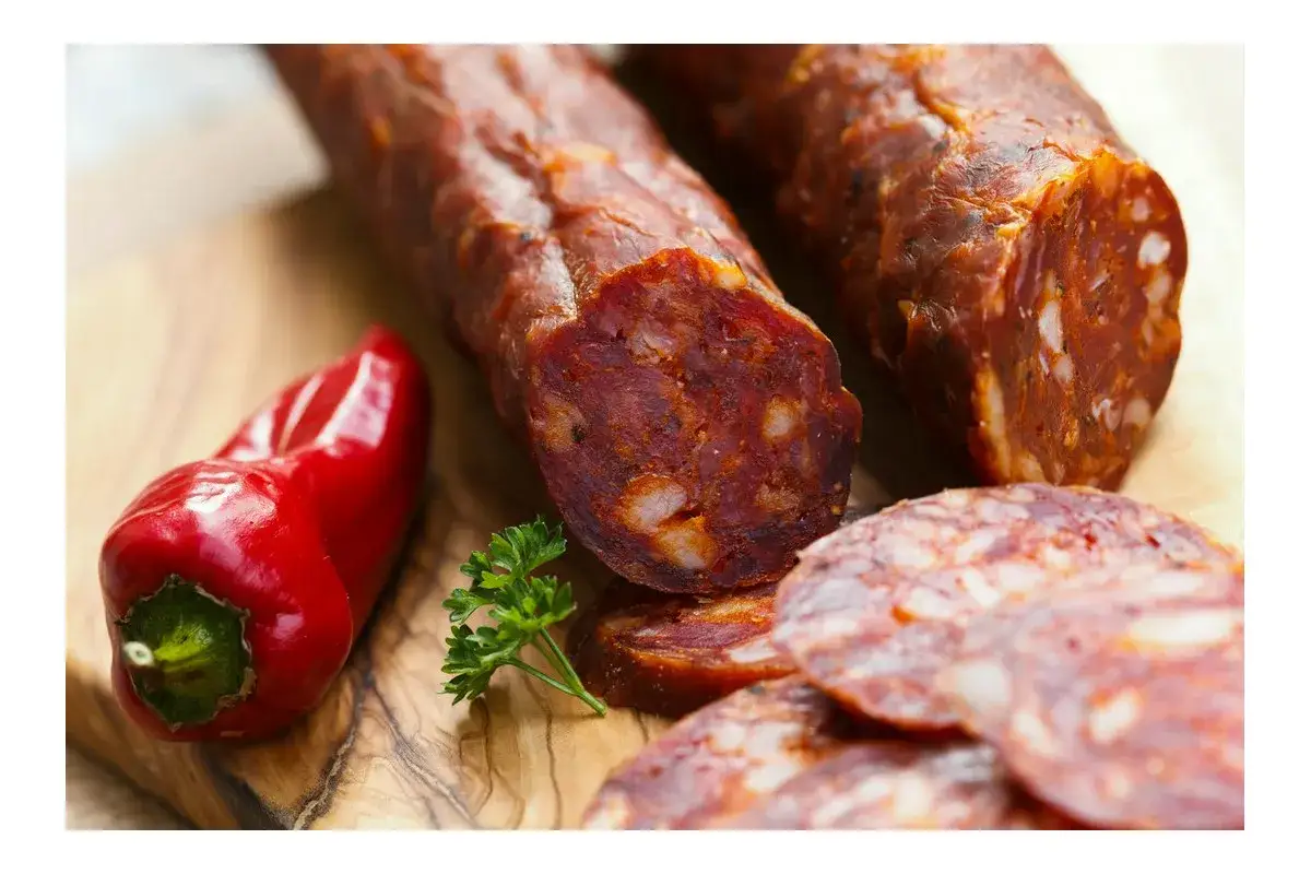 Kawałki pikantnego chorizo, czerwona papryczka i natka pietruszki na desce. To właśnie chorizo, co to za przysmak!