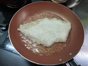 Kotlet w panierce smaży się na patelni w złocistej oliwie z oliwek do smażenia.