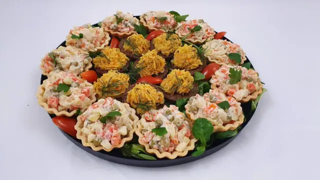 Talerz pełen pysznych przekąsek typu finger food: babeczki z sałatką jarzynową i kanapeczki z pastą.