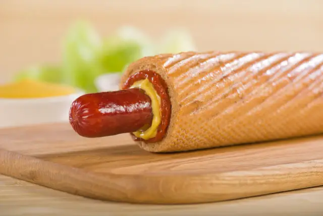 Pyszny hot dog francuski z musztardą i ketchupem na desce.
